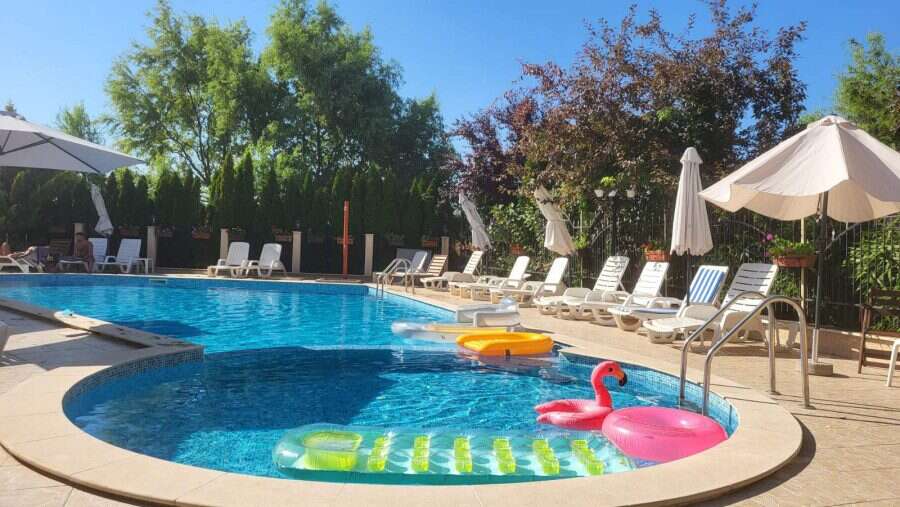 Pool area with lounge chairs, umbrellas, and floating inflatables in Sunny Beach.