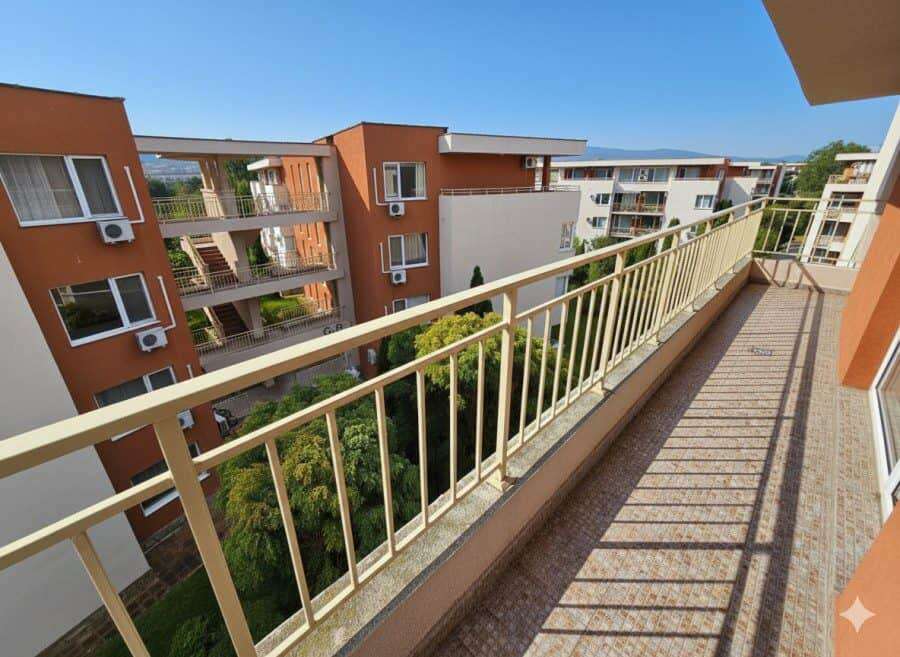Modern apartment balcony overlooking Sunny Beach buildings and greenery. Balcony view from a top-floor studio in Nessebar Fort Club, Sunny Beach, with pool and city views.
