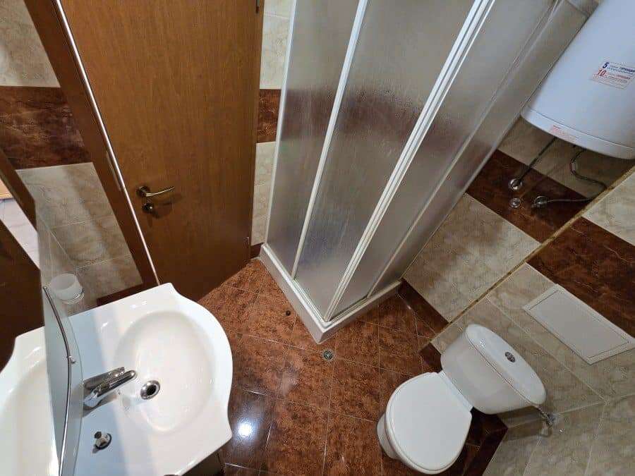 Top floor pool view studio in Nessebar Fort club Compact bathroom with shower, toilet, and sink in Nessebar Fort club.