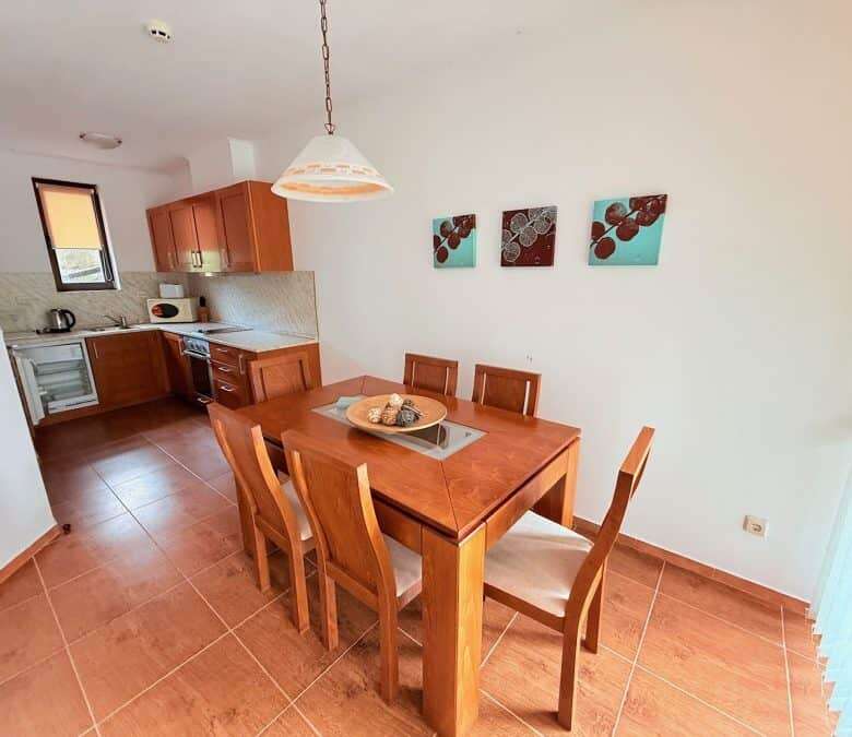 Bright dining space with wooden table and six chairs near the kitchen.