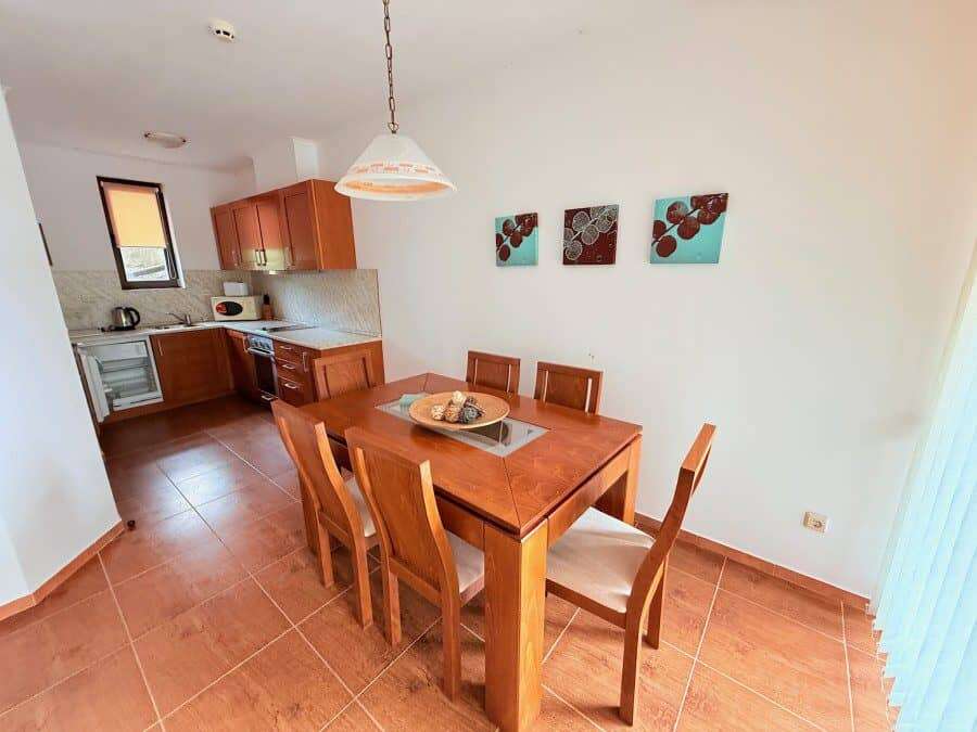 Bright dining space with wooden table and six chairs near the kitchen.