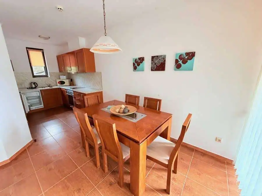 Bright dining space with wooden table and six chairs near the kitchen.