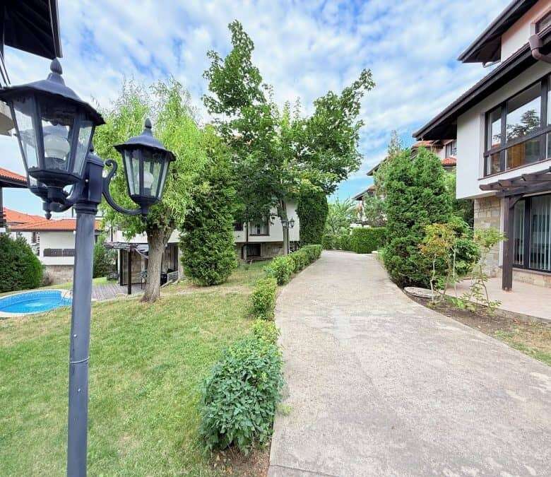 Beautiful garden scene with pathway, trees, and outdoor lighting in a residential area in Bulgaria.