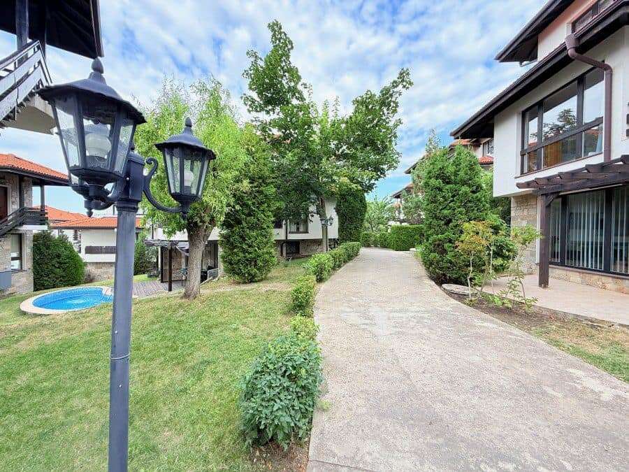 Beautiful garden scene with pathway, trees, and outdoor lighting in a residential area in Bulgaria.