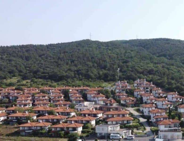 Hillside residential area with terracotta-roofed houses near lush green mountains in Bulgaria.