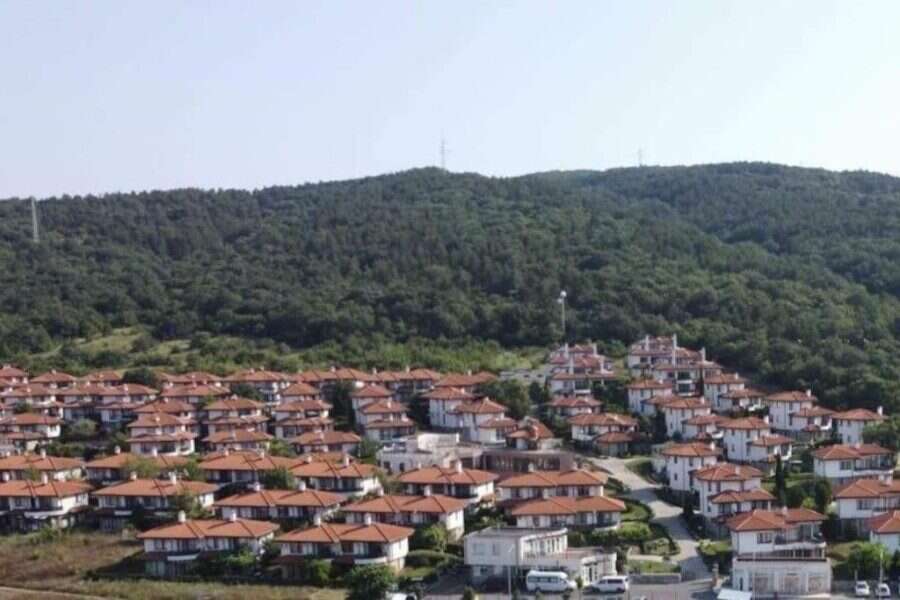 Hillside residential area with terracotta-roofed houses near lush green mountains in Bulgaria.