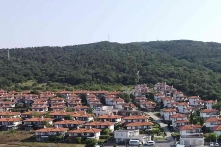 Hillside residential area with terracotta-roofed houses near lush green mountains in Bulgaria.