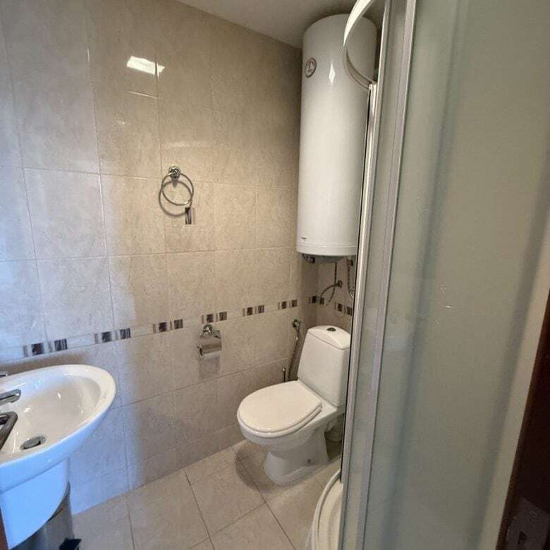 Bathroom with shower, toilet, and water heater in a 2-bedroom apartment.