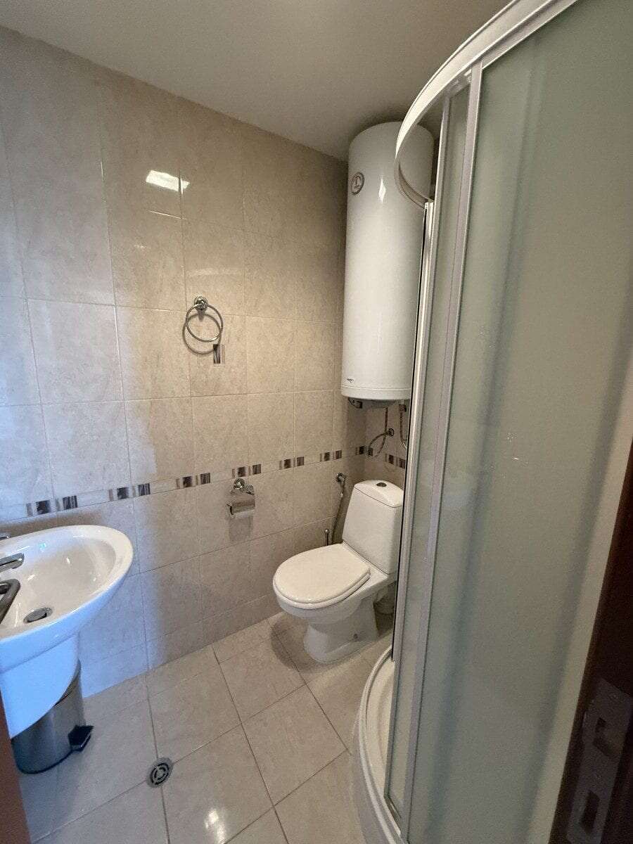 Bathroom with shower, toilet, and water heater in a 2-bedroom apartment.