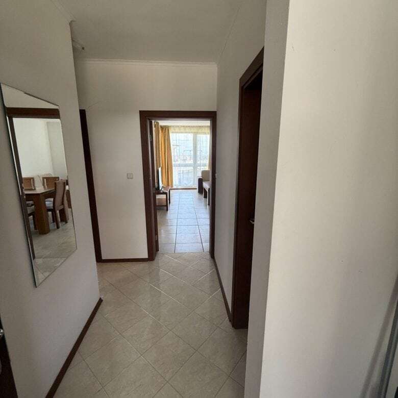Bright hallway leading to living area with large windows and natural light.