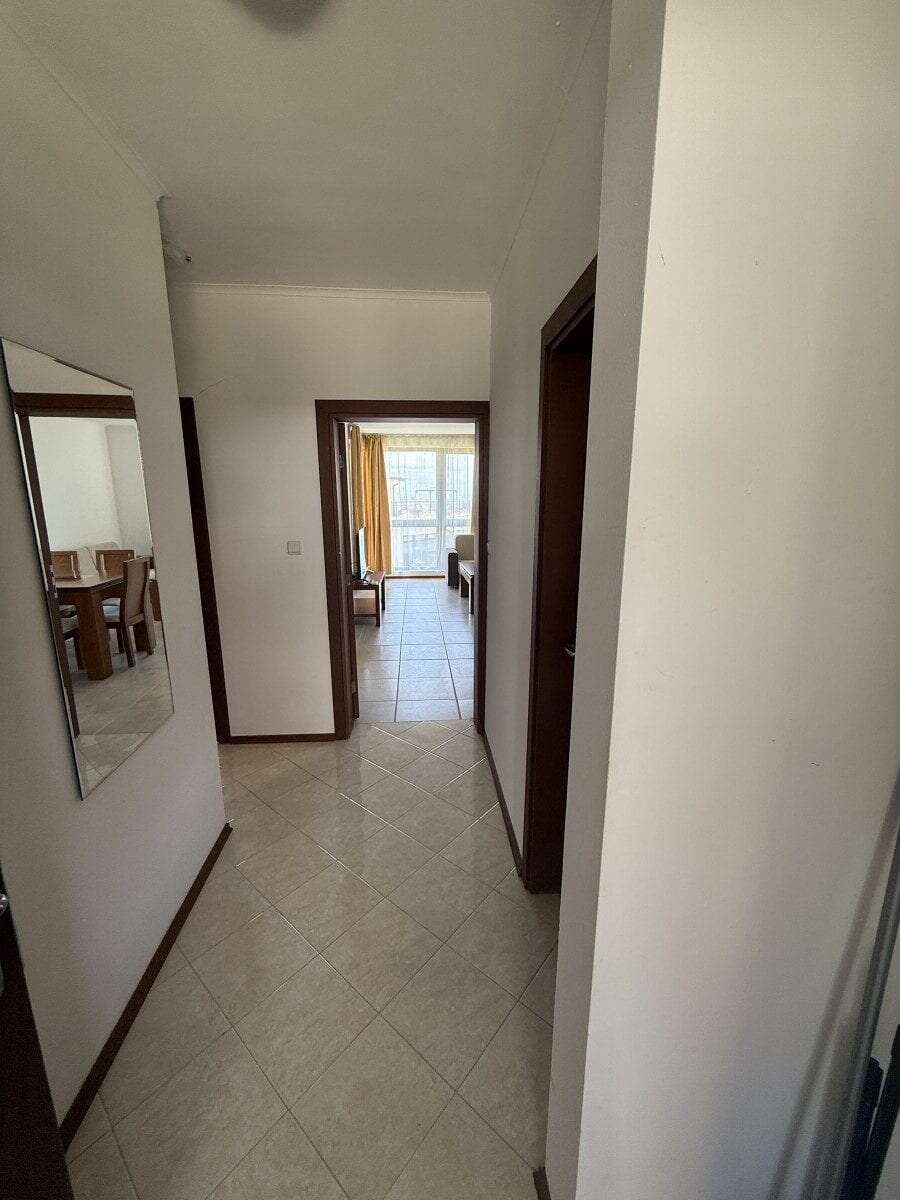 Bright hallway leading to living area with large windows and natural light.