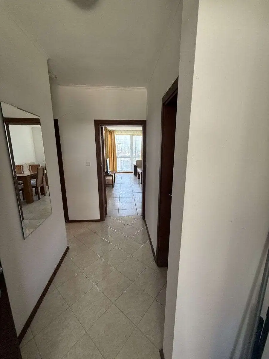 Bright hallway leading to living area with large windows and natural light.