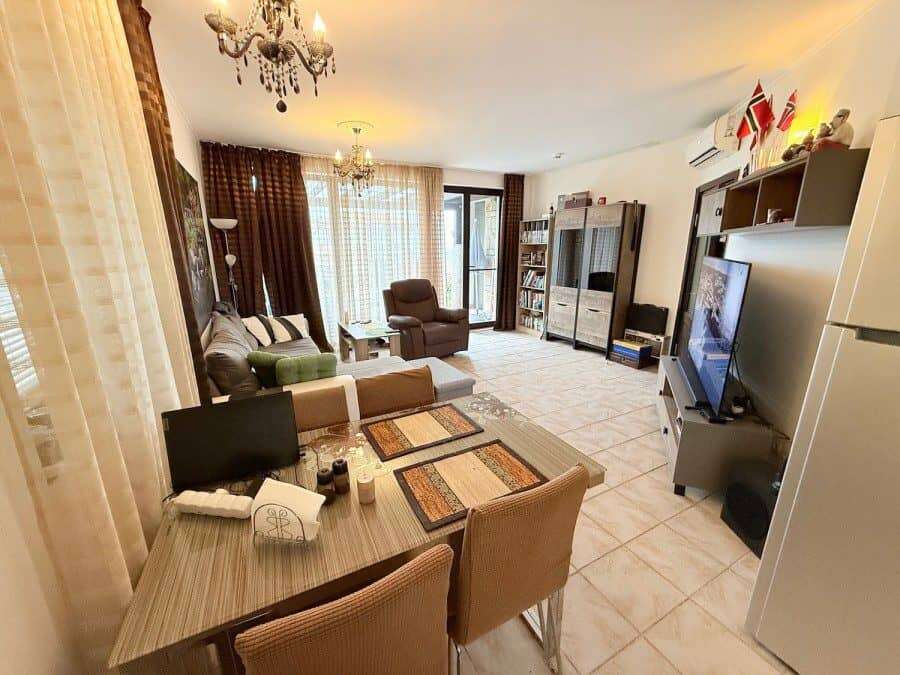 Cozy 2-Bed Ground Floor Apartment in Bulgaria Bright living room with modern furnishings and large windows.