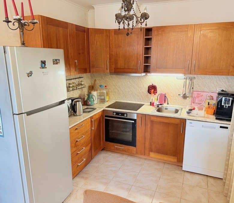 Bright, fully equipped ground floor apartment kitchen with wooden cabinets and essential appliances.