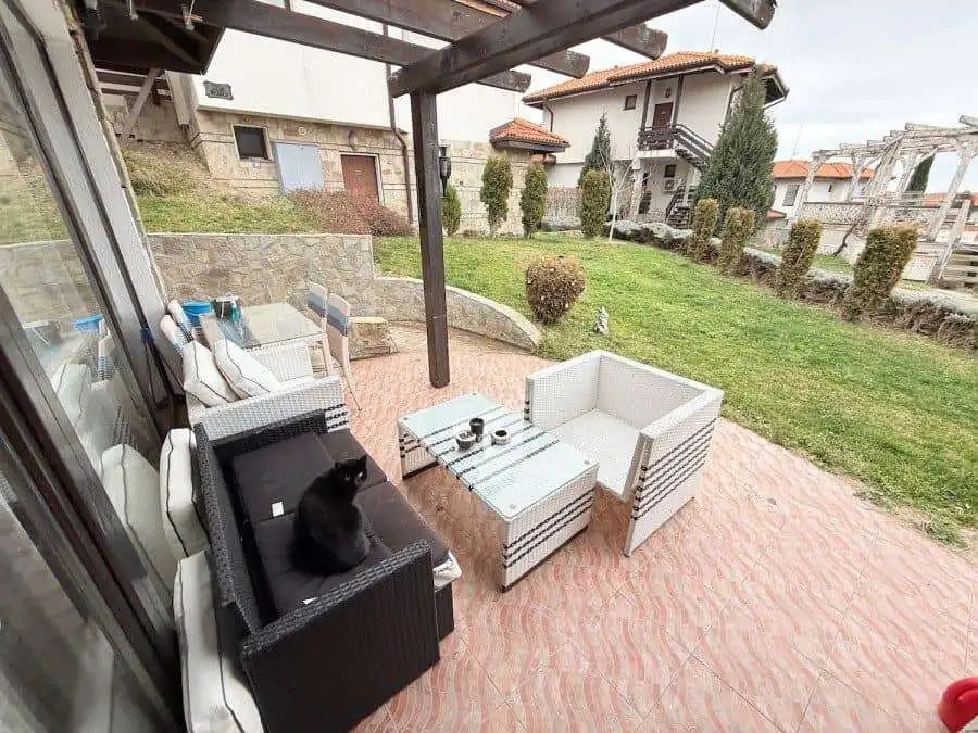 Ground floor apartment terrace with outdoor furniture and cat, near the sea in Bulgaria.