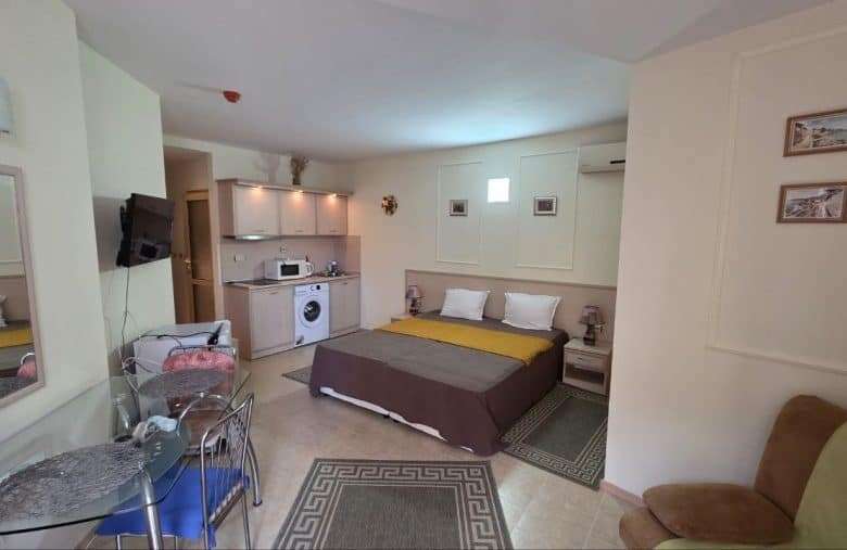 Interior view of a spacious studio apartment in Avalon, Sunny Beach, with a bed, kitchenette, and se.