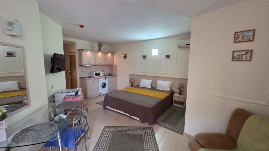 Interior view of a spacious studio apartment in Avalon, Sunny Beach, with a bed, kitchenette, and se.