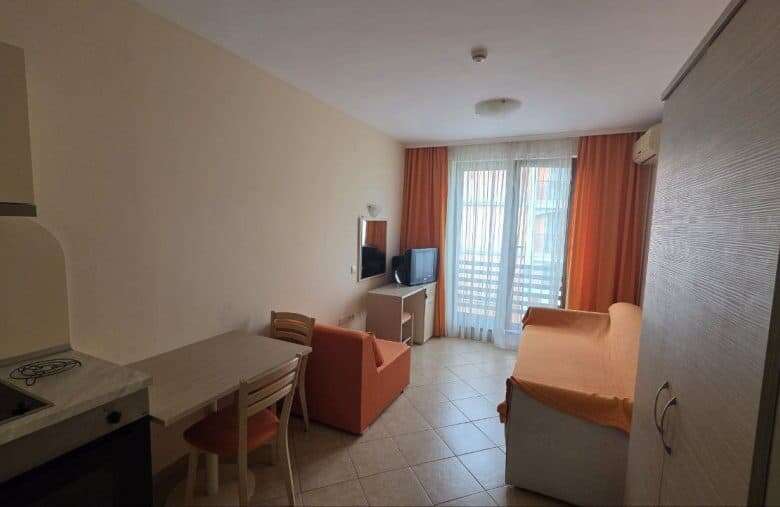 Interior view of a cozy studio apartment with living area and balcony in Sunny Beach, near the sea.