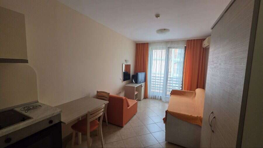 Interior view of a cozy studio apartment with living area and balcony in Sunny Beach, near the sea.