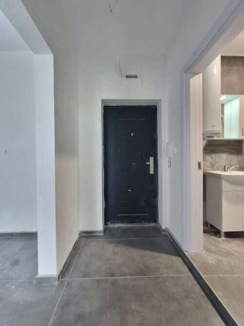 Modern apartment entrance with black door and gray flooring.
