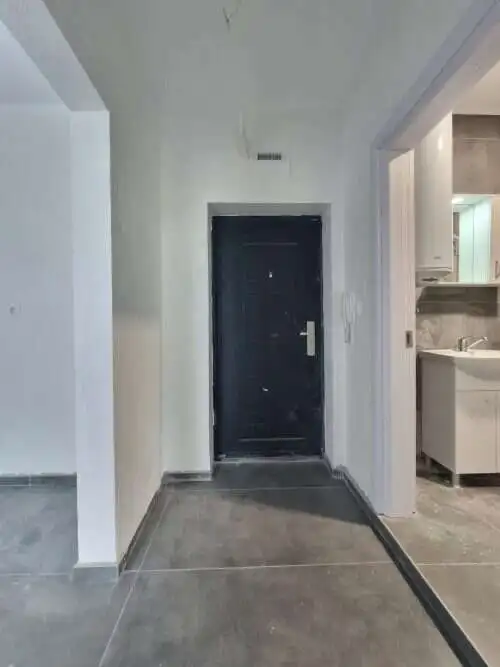 Modern apartment entrance with black door and gray flooring.