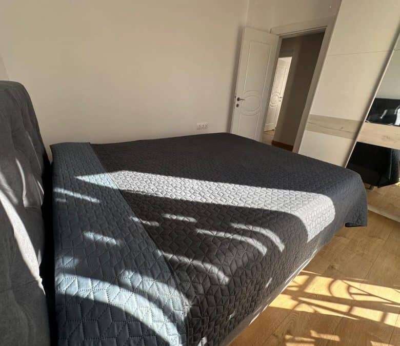 Spacious bedroom featuring a large bed, sunlight, and contemporary decor.