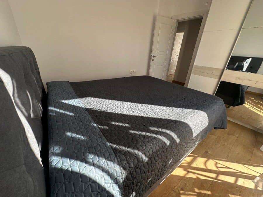 Spacious bedroom featuring a large bed, sunlight, and contemporary decor.