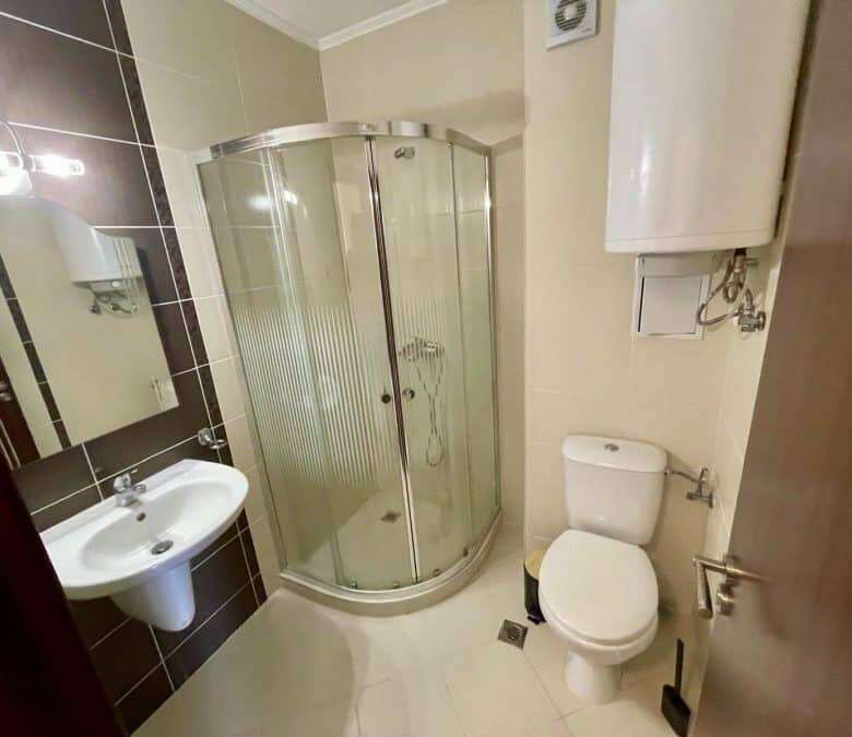 Interior of a 2-bedroom apartment with sea and pool views, featuring a shower, toilet, and sink.