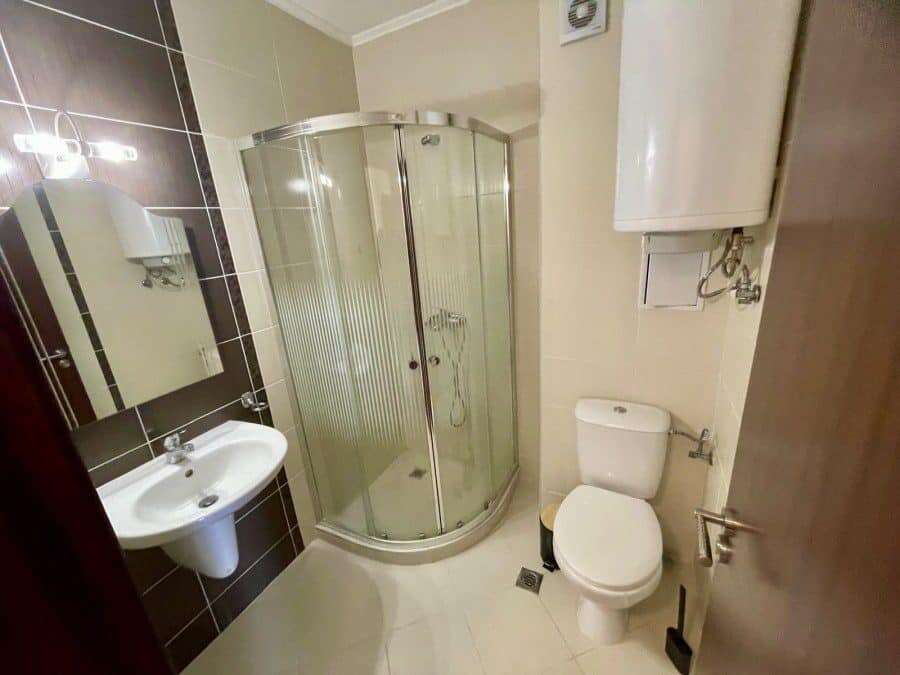 Interior of a 2-bedroom apartment with sea and pool views, featuring a shower, toilet, and sink.