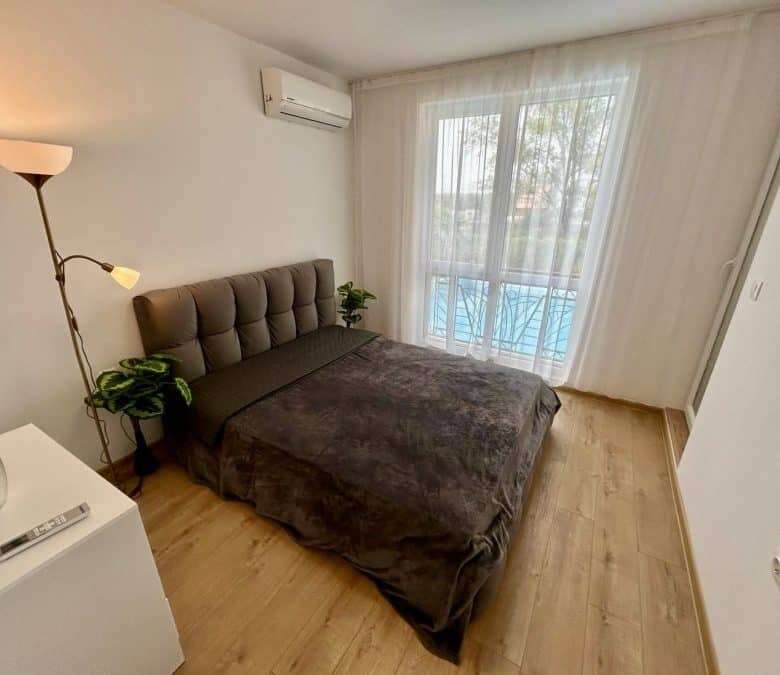 Comfortable bedroom featuring a large bed, stylish decor, and balcony overlooking the pool area. Per.