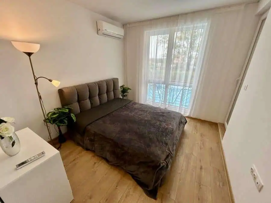 Comfortable bedroom featuring a large bed, stylish decor, and balcony overlooking the pool area. Per.
