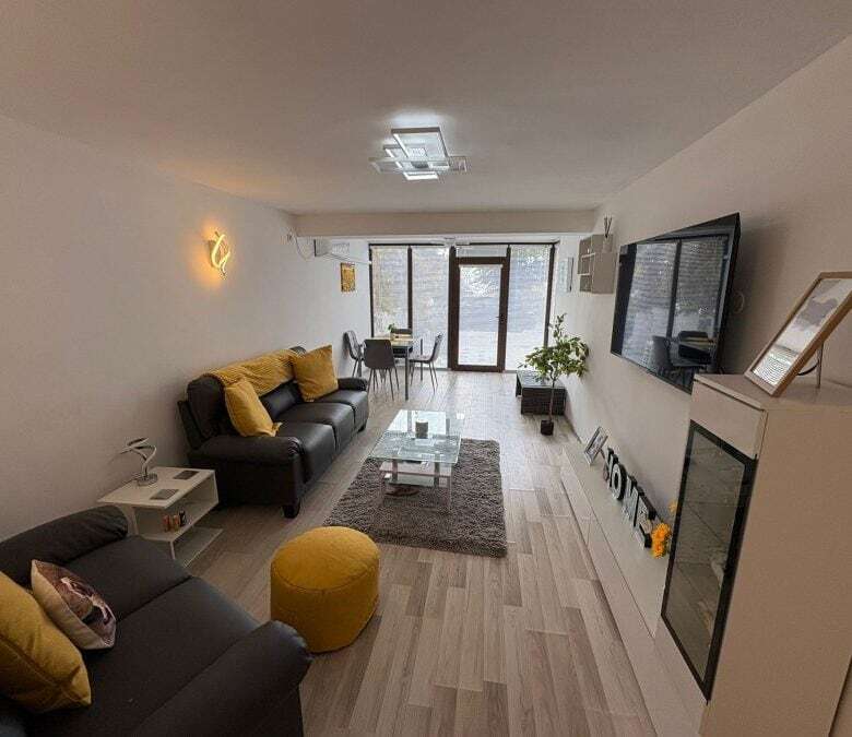 Bright living room with sofa, TV, and balcony in Sveti Vlas, Bulgaria.