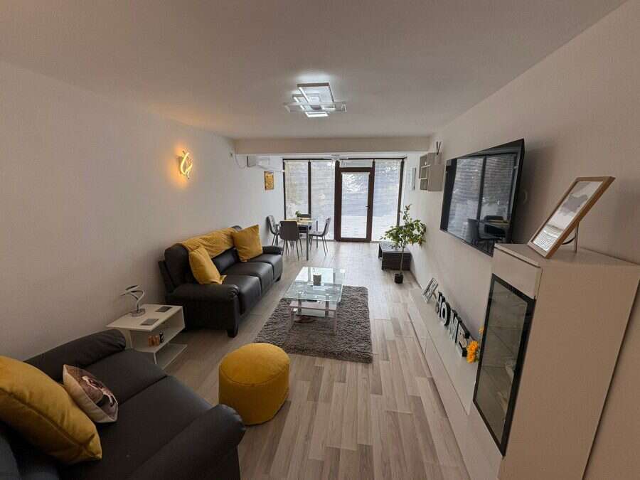 Bright living room with sofa, TV, and balcony in Sveti Vlas, Bulgaria.