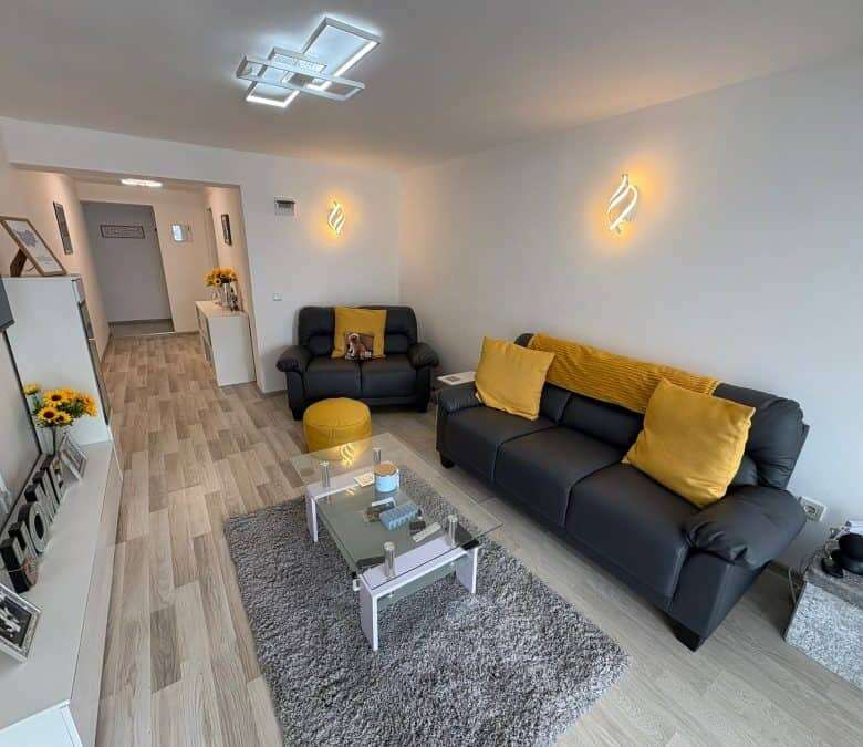 Bright living room with black sofas, yellow cushions, and contemporary lighting in Sveti Vlas.