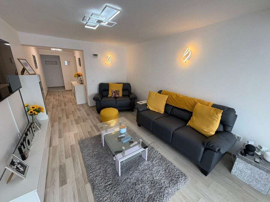 Bright living room with black sofas, yellow cushions, and contemporary lighting in Sveti Vlas.