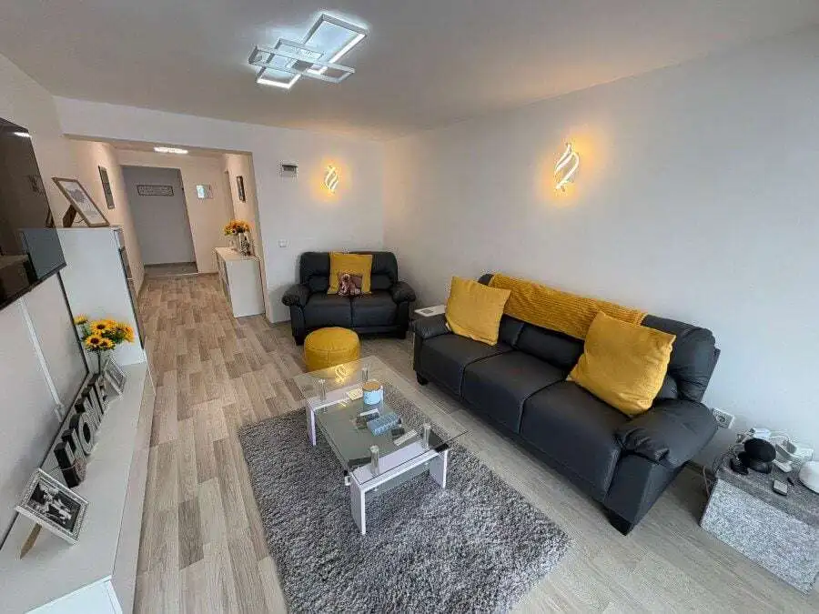 Bright living room with black sofas, yellow cushions, and contemporary lighting in Sveti Vlas.