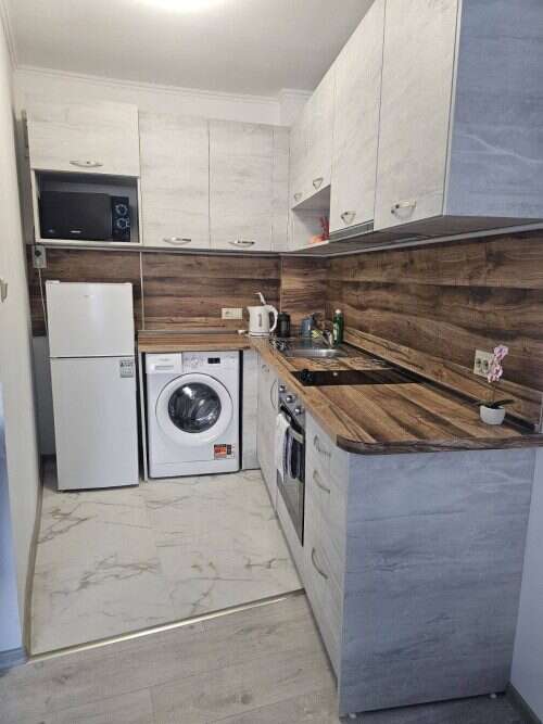 Bright, compact kitchen with white cabinets and wooden accents in Yassen, Sunny Beach.