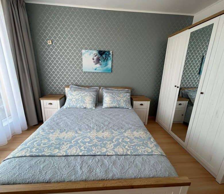 Bright bedroom with elegant furniture and large wardrobe.