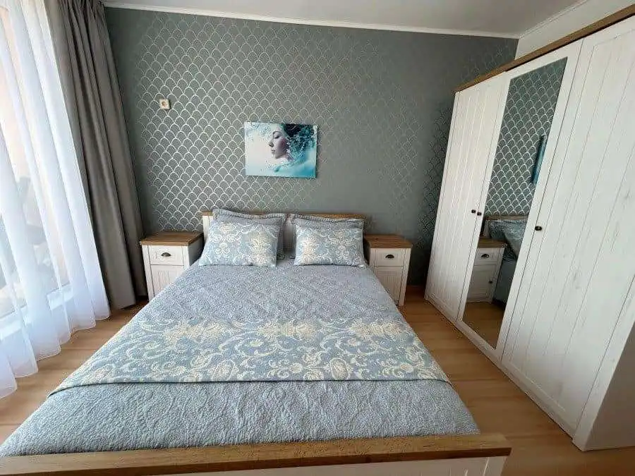 Bright bedroom with elegant furniture and large wardrobe.