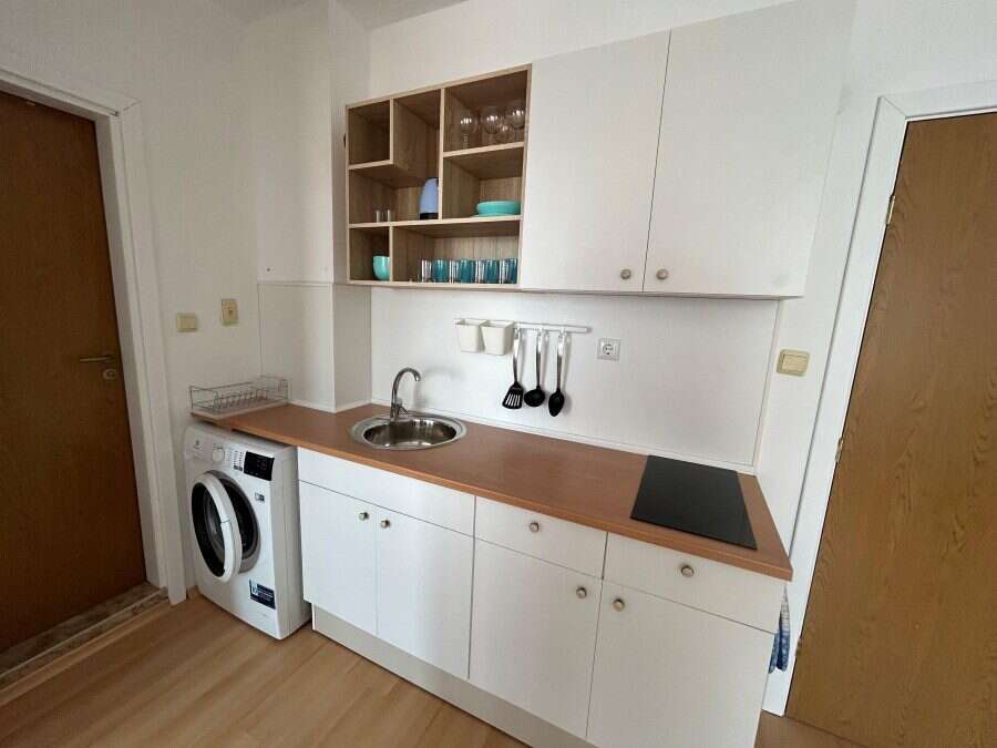 Cozy kitchen in a sunny 1-bedroom top floor apartment with modern decor and compact appliances.