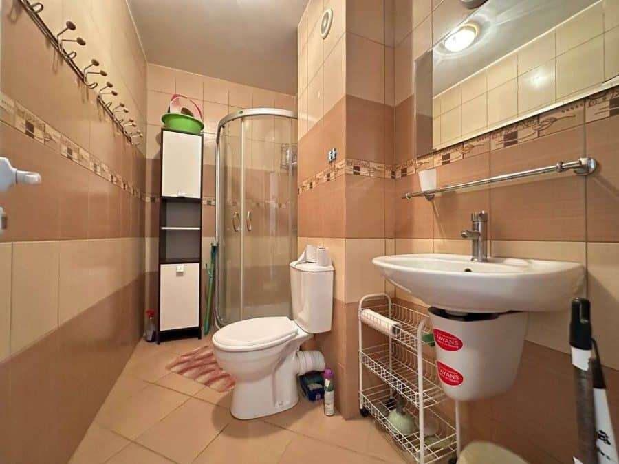 Small bathroom with shower, toilet, and sink in a furnished Sunny Beach apartment.