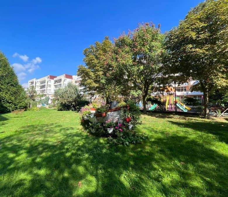 Green garden with trees and flowers near Grand Kamelia in Sunny Beach.
