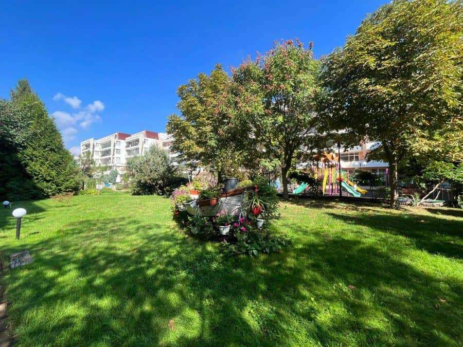 Green garden with trees and flowers near Grand Kamelia in Sunny Beach.