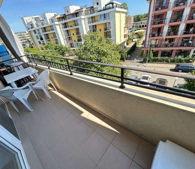Balcony of a furnished 1-bedroom apartment in Sunny Beach with city views and outdoor seating.
