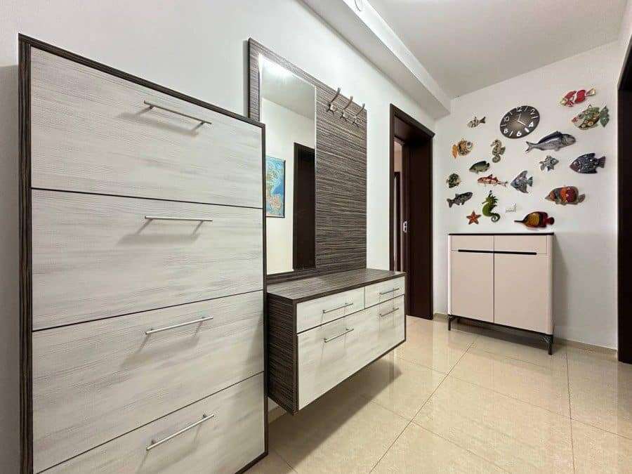 Modern apartment hallway with fish-themed wall decor and sleek furniture. Stylish hallway interior featuring fish wall art, a mirror, and contemporary storage units.