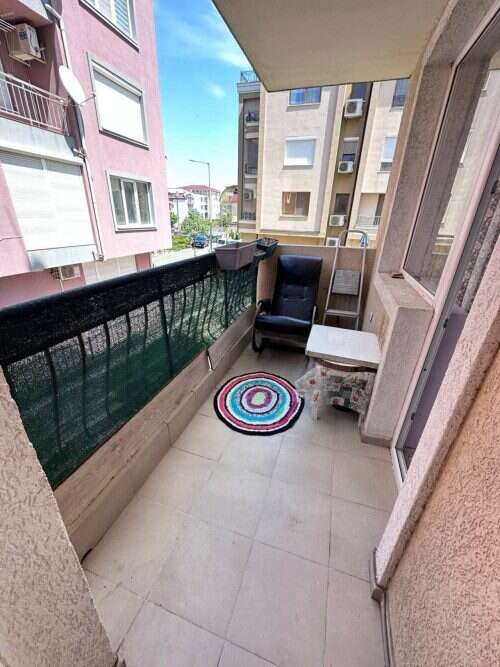 Balcony with seating and colorful rug, overlooking nearby apartment buildings, 300 meters from the s.