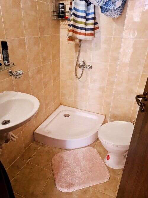 Bathroom with shower, toilet, and sink in a furnished 1-bedroom apartment.