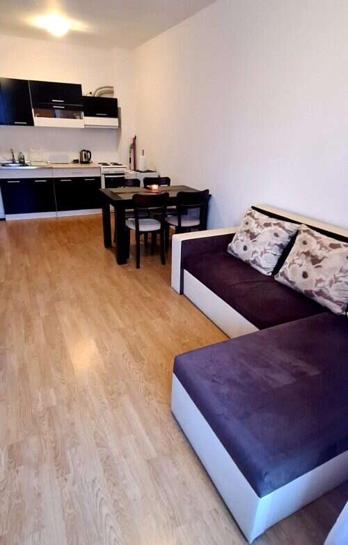 Bright living room with sofa and cushions, open-plan kitchen, ideal for comfortable seaside living.