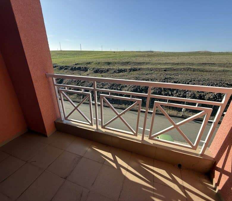 Balcony overlooking open fields and clear blue sky, perfect for relaxing outdoors.