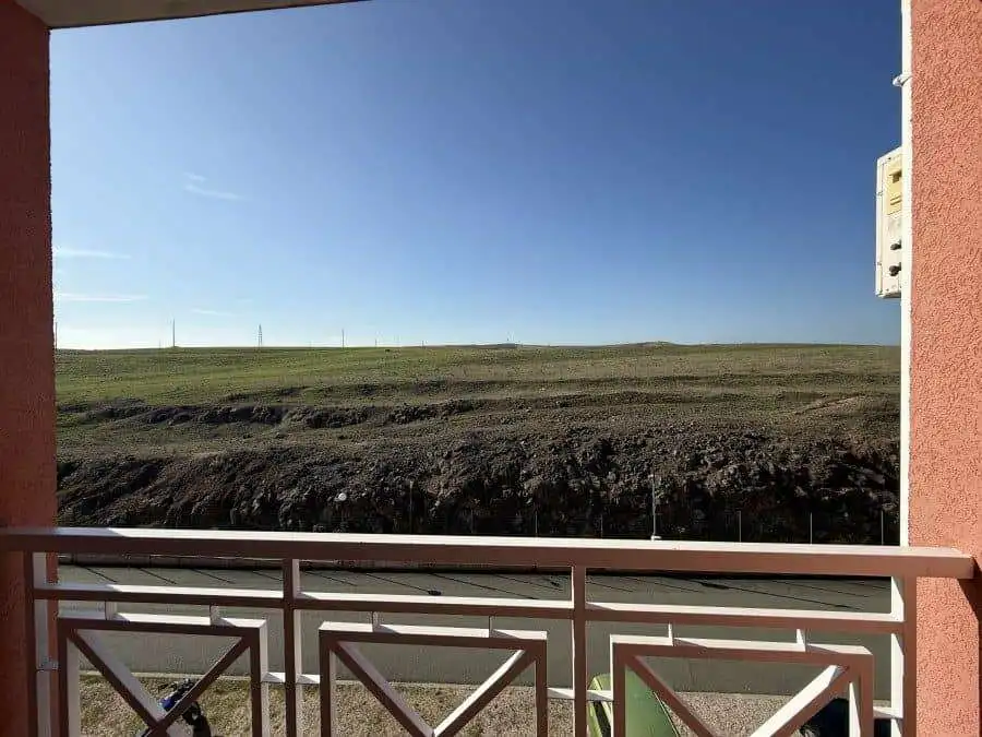 Balcony view from a fully furnished 1-bedroom, 2-bath apartment overlooking open fields on a sunny d.